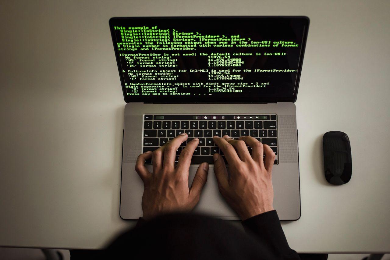 Hands typing on a laptop showing code